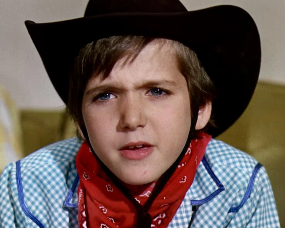 Paris Themmen as Mike Teevee wearing a black cowboy hat and red bandana in Willy Wonka & The Chocolate Factory.