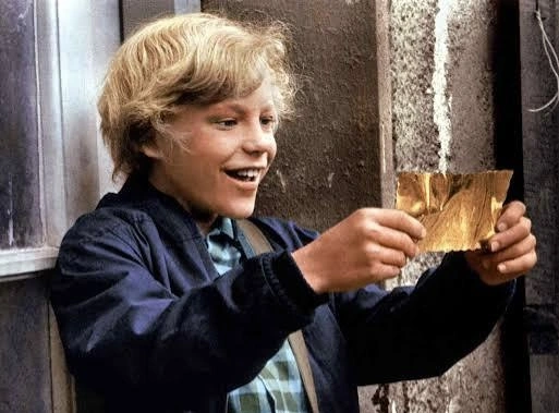 Peter Ostrum as Charlie Bucket holding a golden ticket in Willy Wonka & The Chocolate Factory.