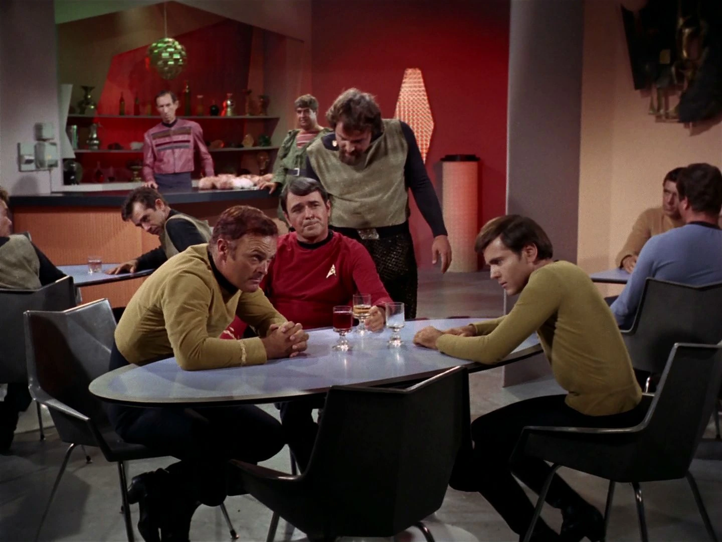 Chekov seated with Scotty and fellow Enterprise crew members as a Klingon stands behind their table in The Trouble with Tribbles.